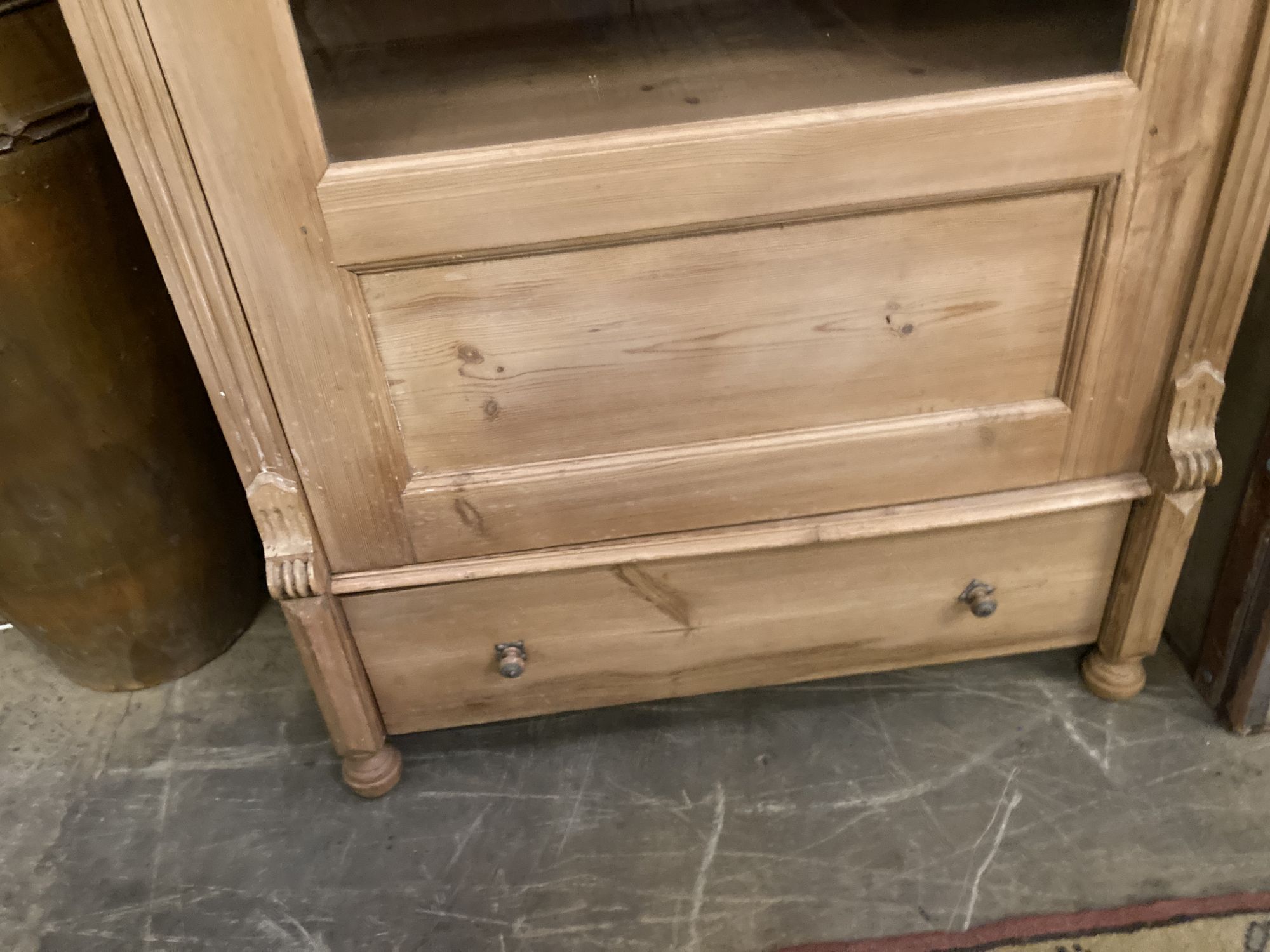 A pine display cabinet, fitted single glazed door enclosing four shelves over base drawer, width 100cm, depth 55cm, height 183cm